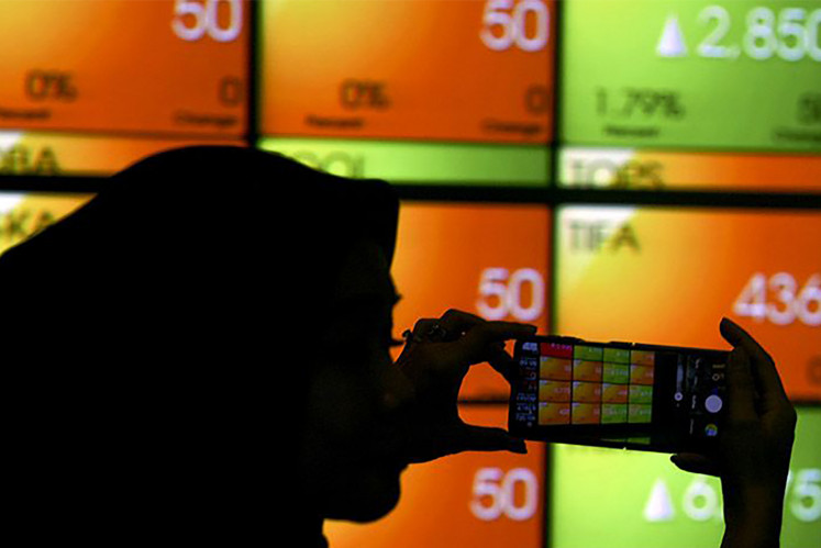 An employee takes a photo of a screen displaying stock movements on July 4, 2023, at the Indonesian Stock Exchange (IDX) in Jakarta. The IDX Composite inched 0.14 percent down to 7,209.6 on Dec. 21, 2023, after central bankers decided to maintain the benchmark interest rate at 6 percent.