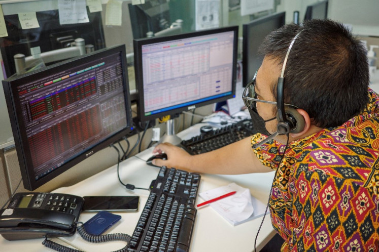 A trader looks at screens while monitoring stock movements in Jakarta on March 16, 2023.